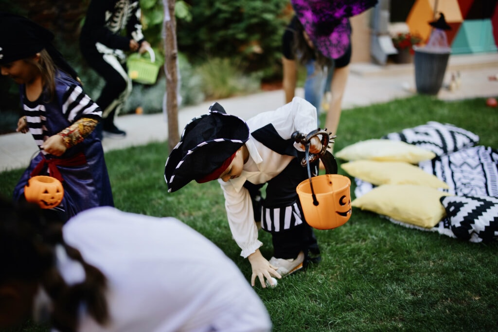 Children in Halloween costumes search a park for treasure