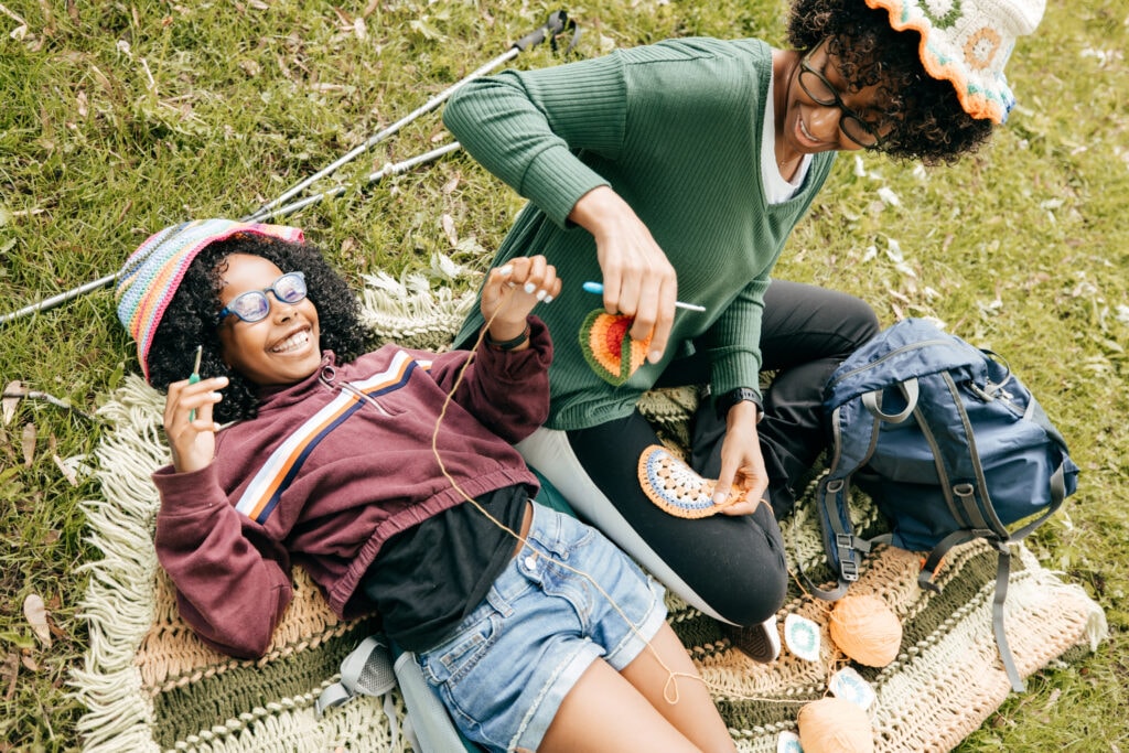 A mother and daughter knit in in a park