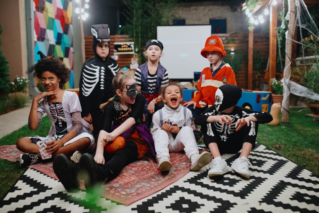 A group of kids in costumes in a backyard pose for a photo