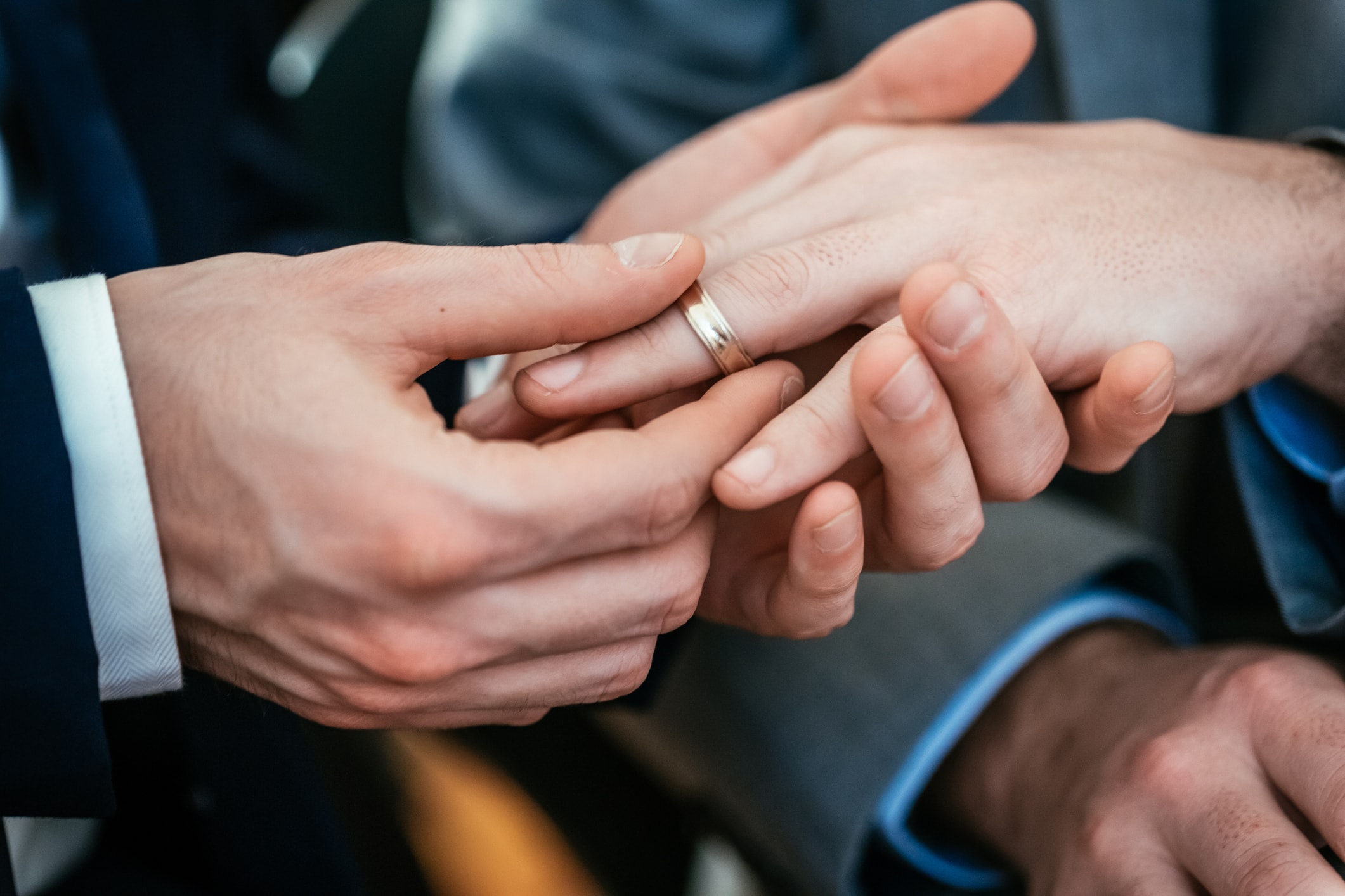Close-up of a hand placing a ring on another hand.