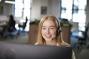 Personne portant un casque d’écoute dans un espace de bureau moderne, regardant vers la caméra.