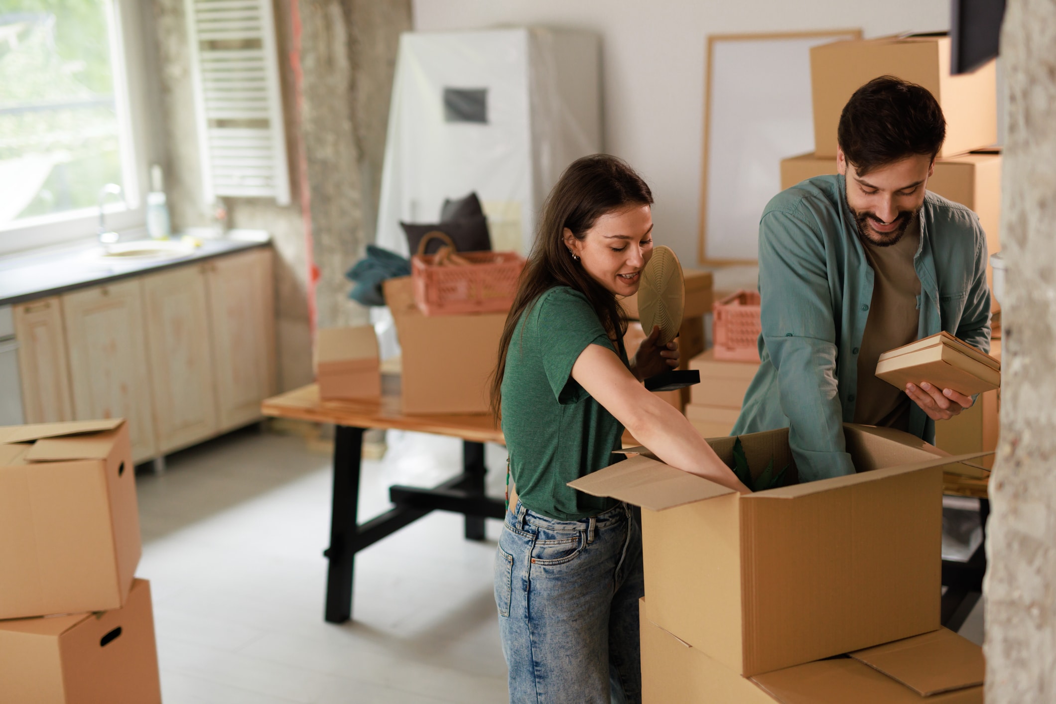 Two people packing cardboard boxes together in a home.
