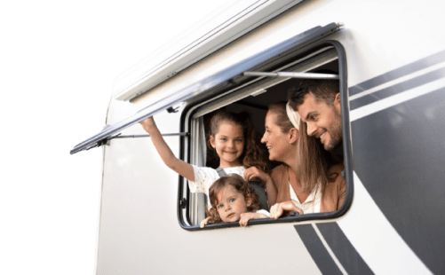 a man, woman, and two kids looking out a window of their RV