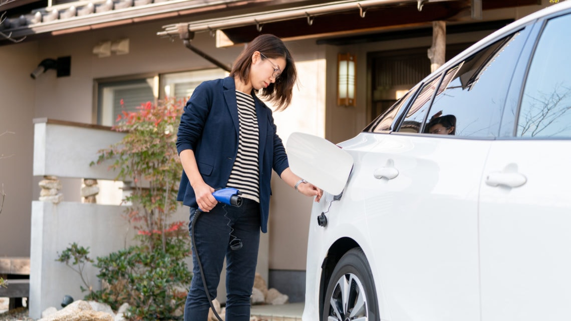 A young woman charging her EV