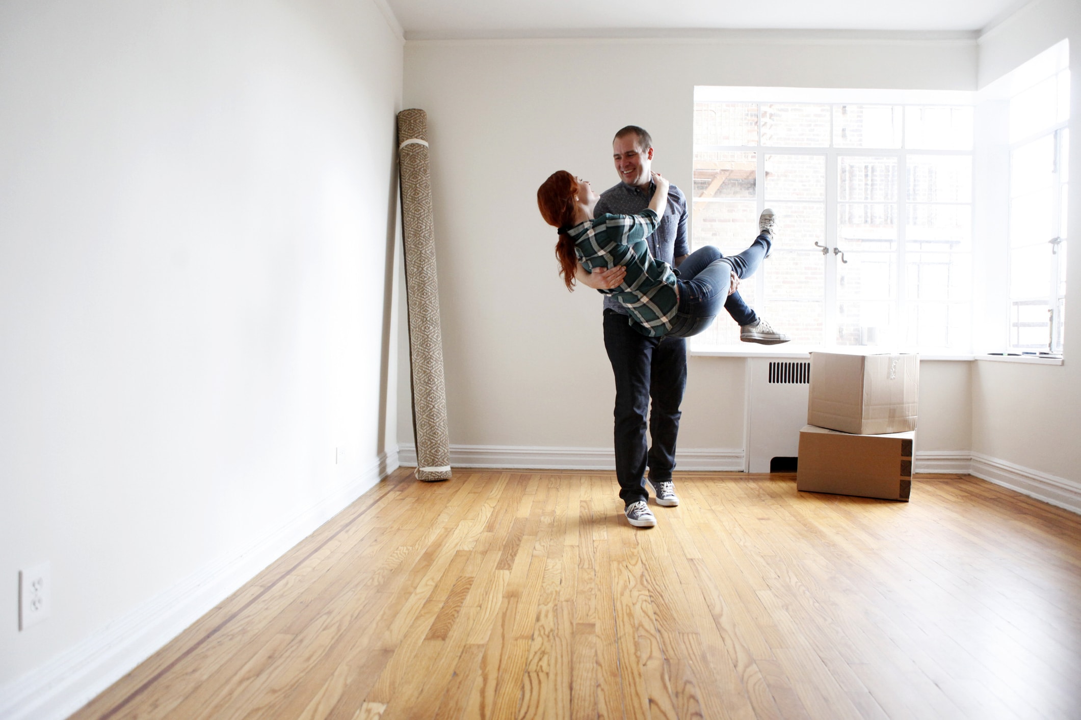 A man carries a woman across an empty family room