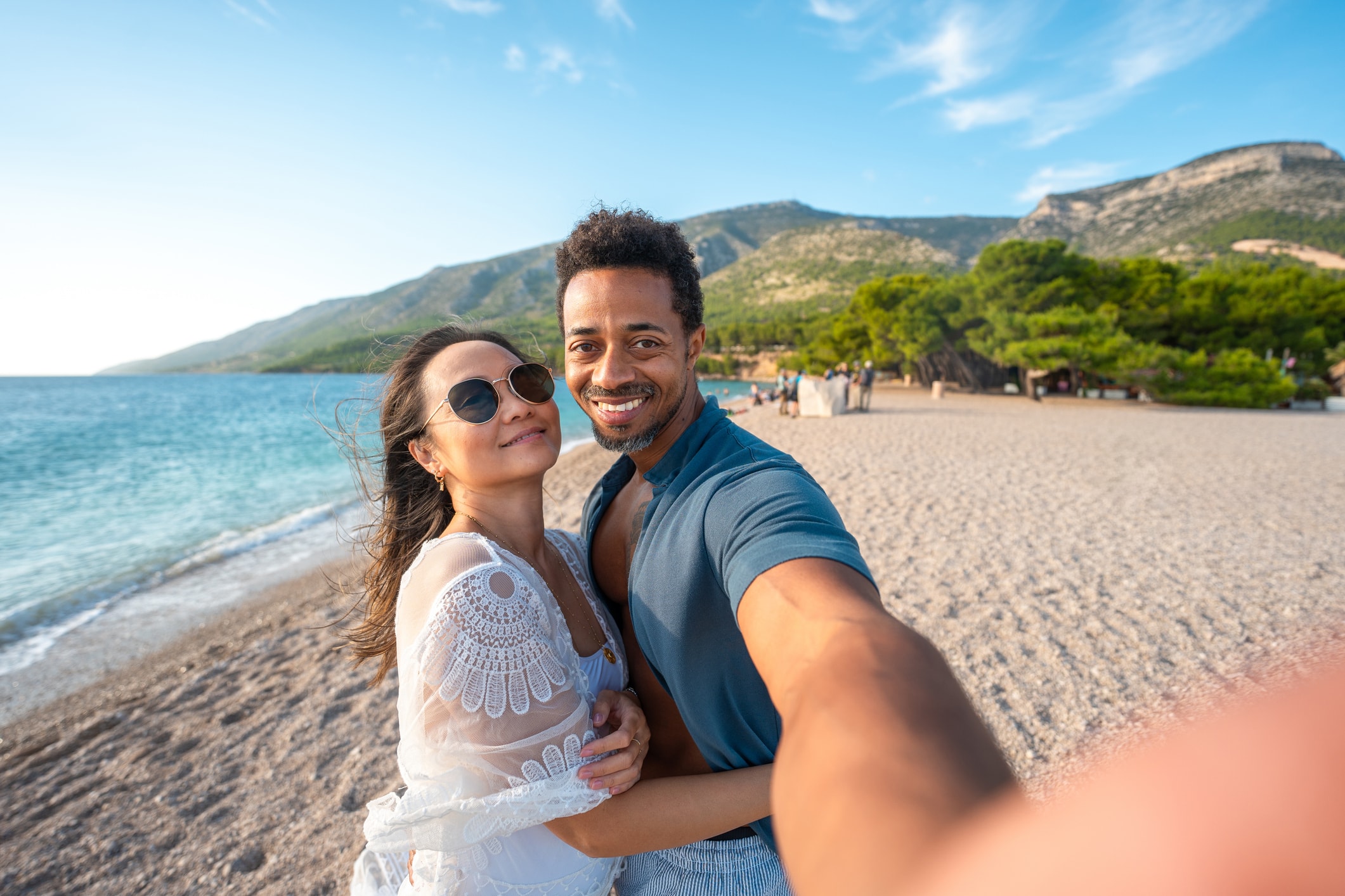 A man and woman take a selfie on a beach