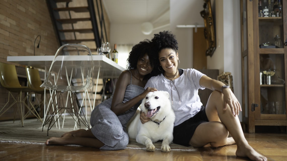Deux femmes sont assises sur le sol avec un chien blanc