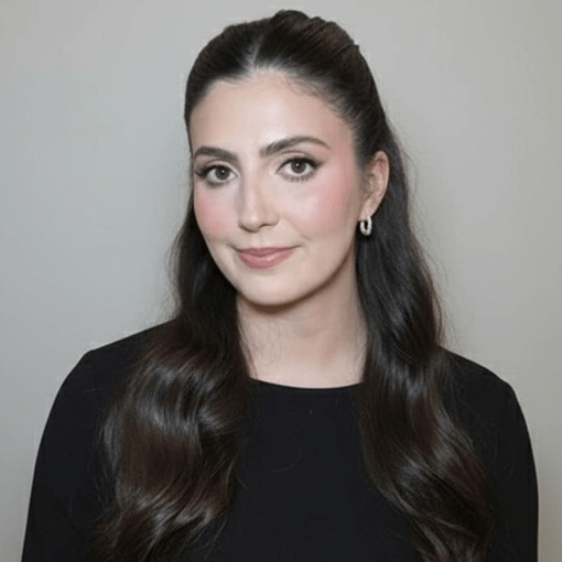 Portrait of a person with long dark hair wearing a black top against a plain background.