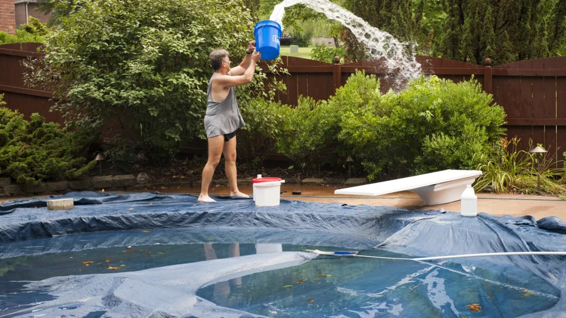 A homeowner cleaning their pool cover