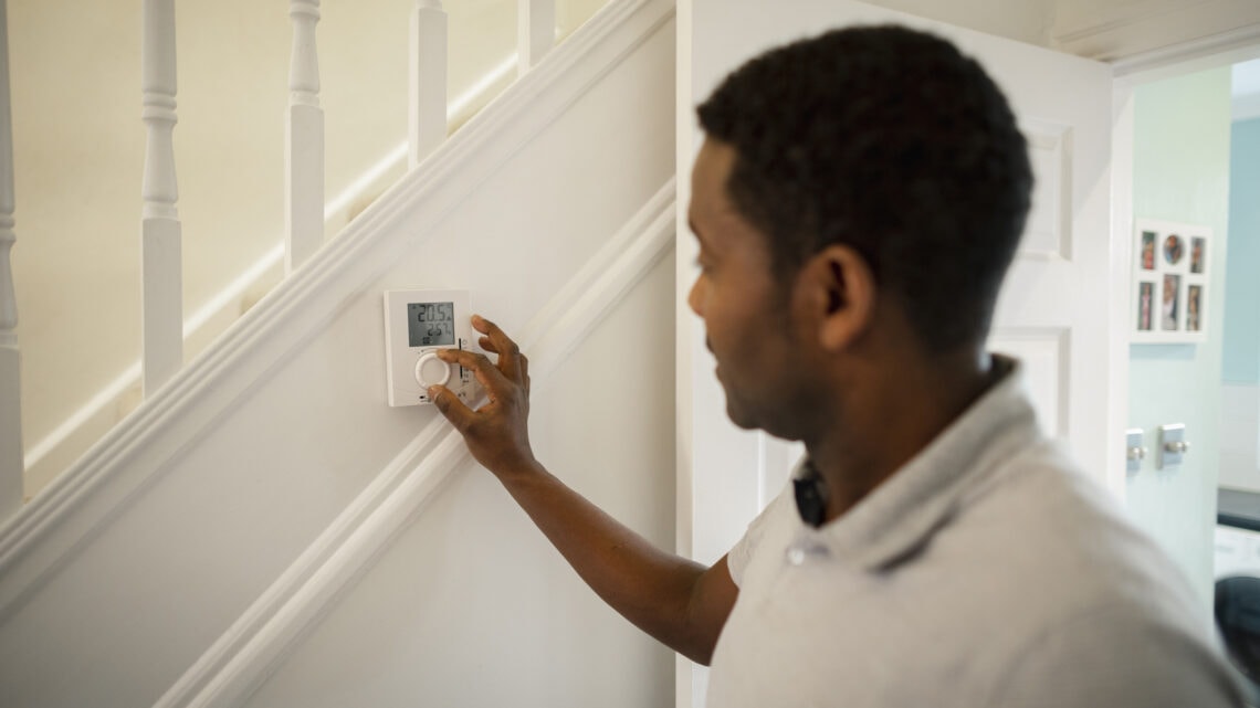Un homme qui ajuste le thermostat dans sa maison