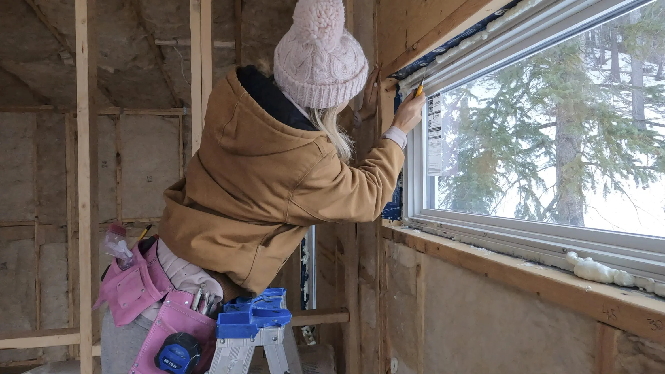 Person using a tool around a window during home renovations.