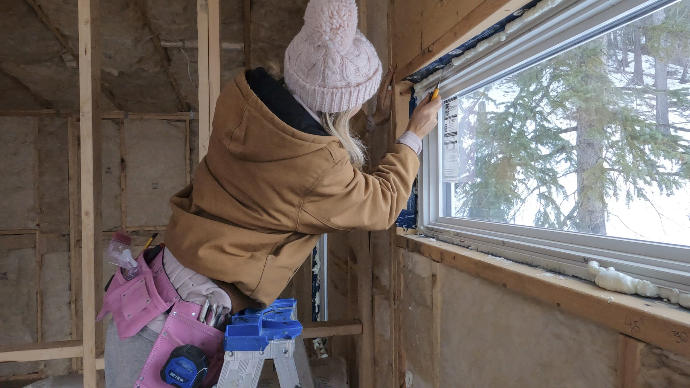 Person using a tool around a window during home renovations.