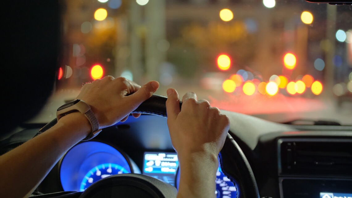 Two hands holding the driving wheel of a car