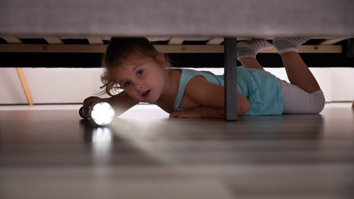 Un enfant qui cherche des cadeaux sous un lit
