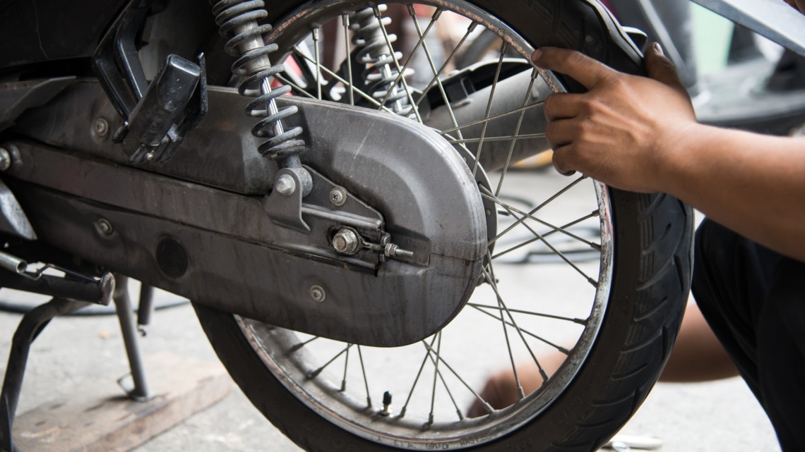 Les mains d’un technicien travaillant sur la roue arrière d’une moto