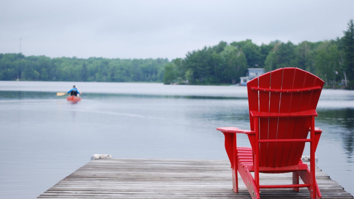 An empty red chair on a dock, floating on a lake