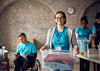 woman in a blue shirt holding a box with clothes