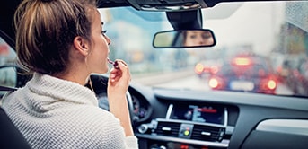 a woman in a car applying lipstick