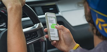 man driving while texting on his phone