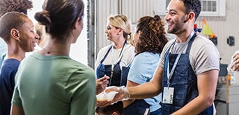 a group of people in aprons serving food to homeless women