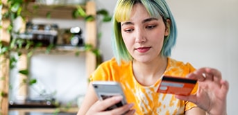 a woman with green hair holding a credit card and a phone