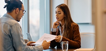 woman being interviewed by a man holding her resume
