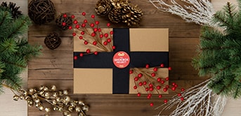 a shoebox with red berries and pine cones on a wood table