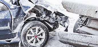 a car with a damaged front end in the snow