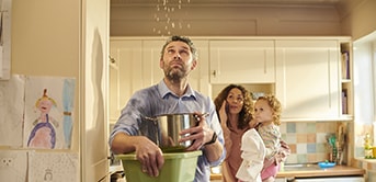 a man holding a pot with a child and a woman standing in the background