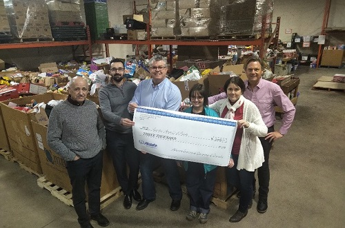 a group of Allstate employees holding a large check inside a warehouse